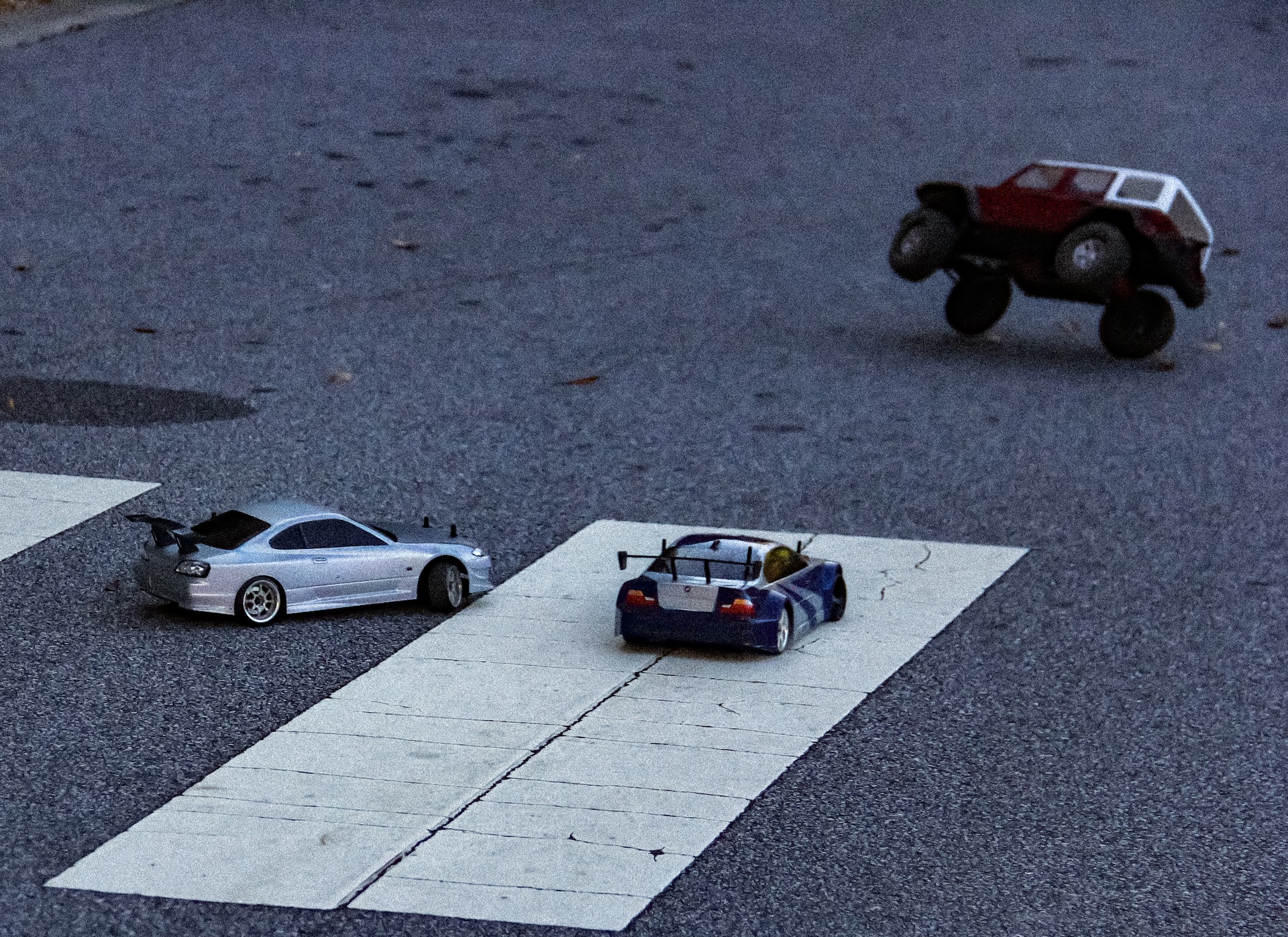 On-road RC cars and an off-road truck on tarmac